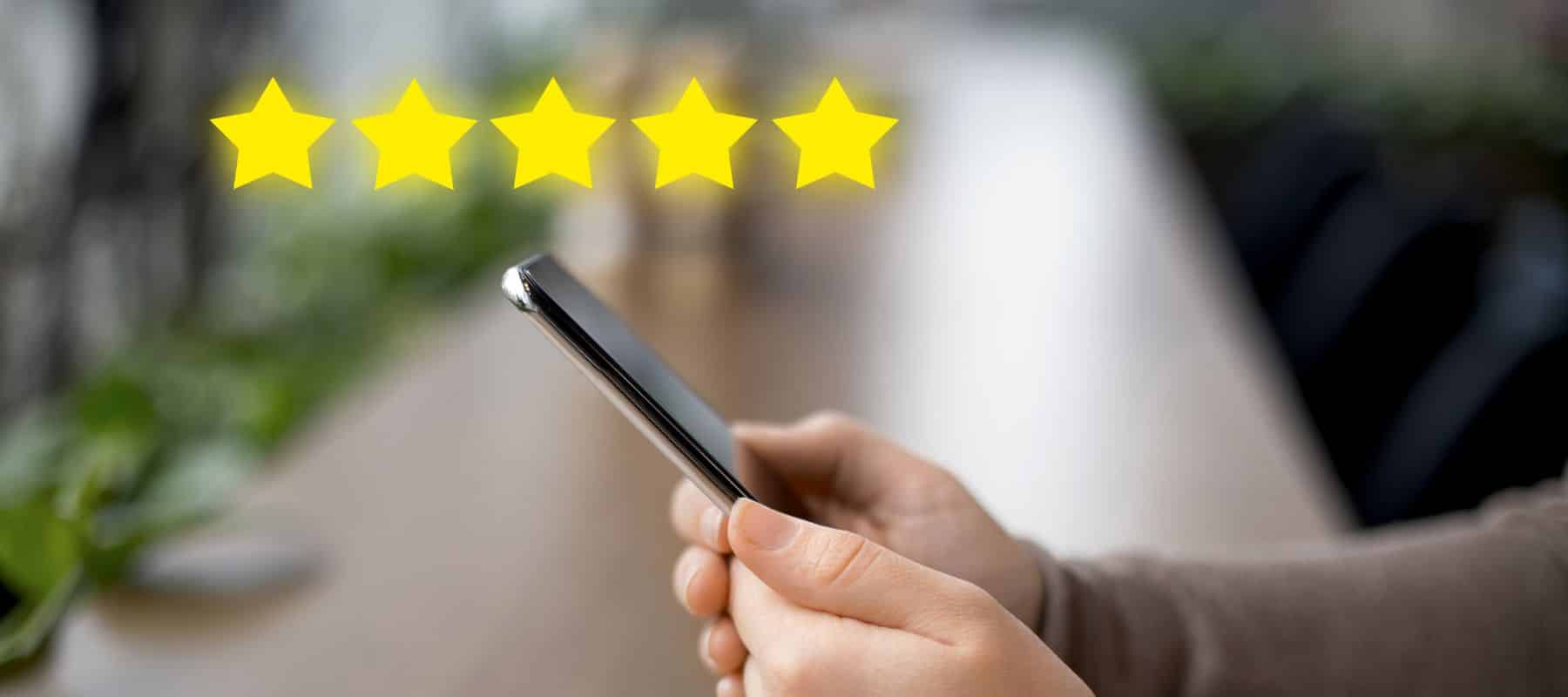 Hand holding a smartphone with a five-star review overlay